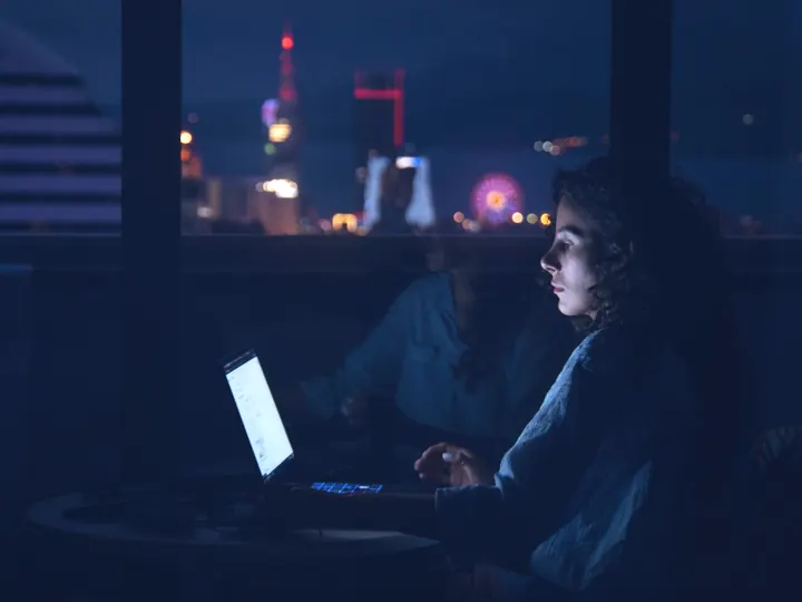 A buyer researching suppliers on a laptop late in the evening